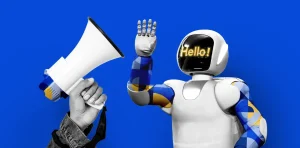 A hand holding a megaphone with a robotic figure waving, the robot has a digital face with the text "Hello!" on a bright blue background.