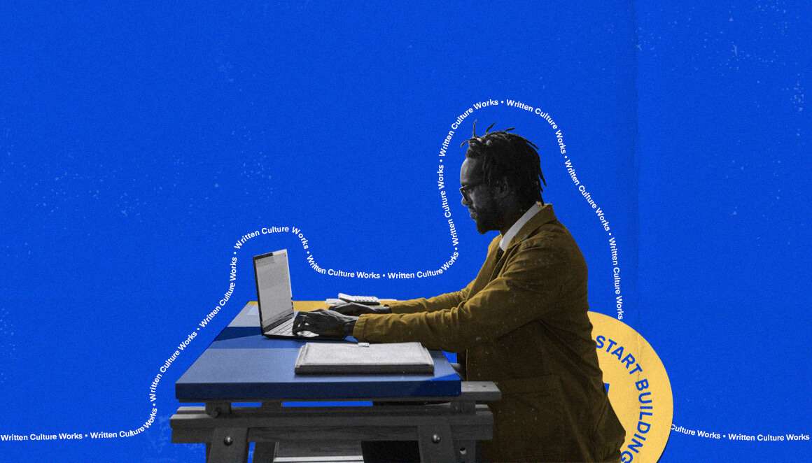 A man in a mustard-colored jacket and glasses is seated at a desk, working on a laptop in front of a solid blue background with yellow circular graphics and text repeating "Written Culture Works".